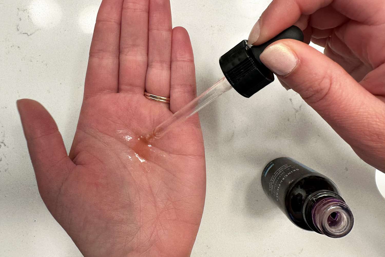 Dropper dispensing SkinCeuticals Hyaluronic Acid Intensifier Serum onto hand