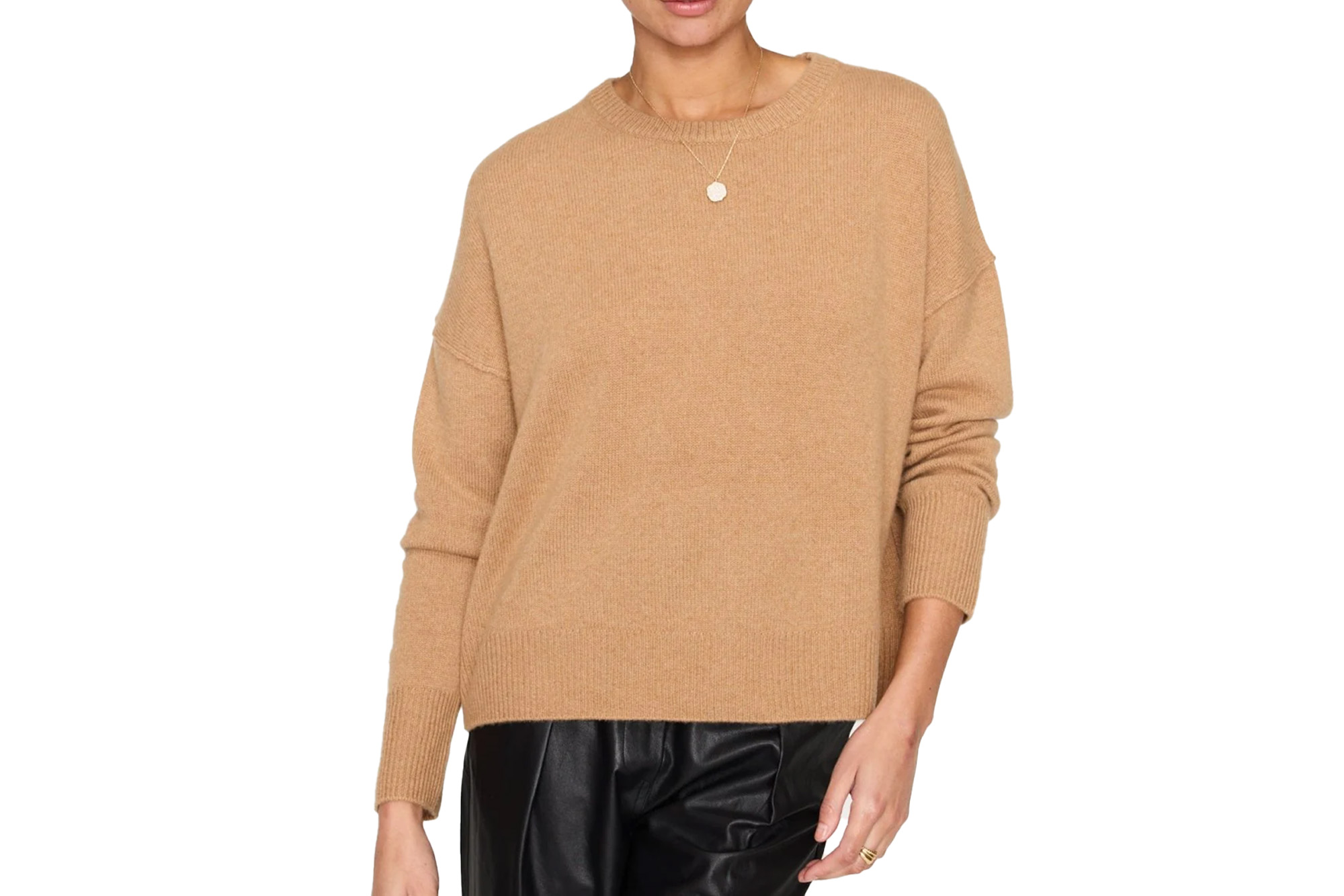 A person wearing a tan crewneck sweater and black leather pants.