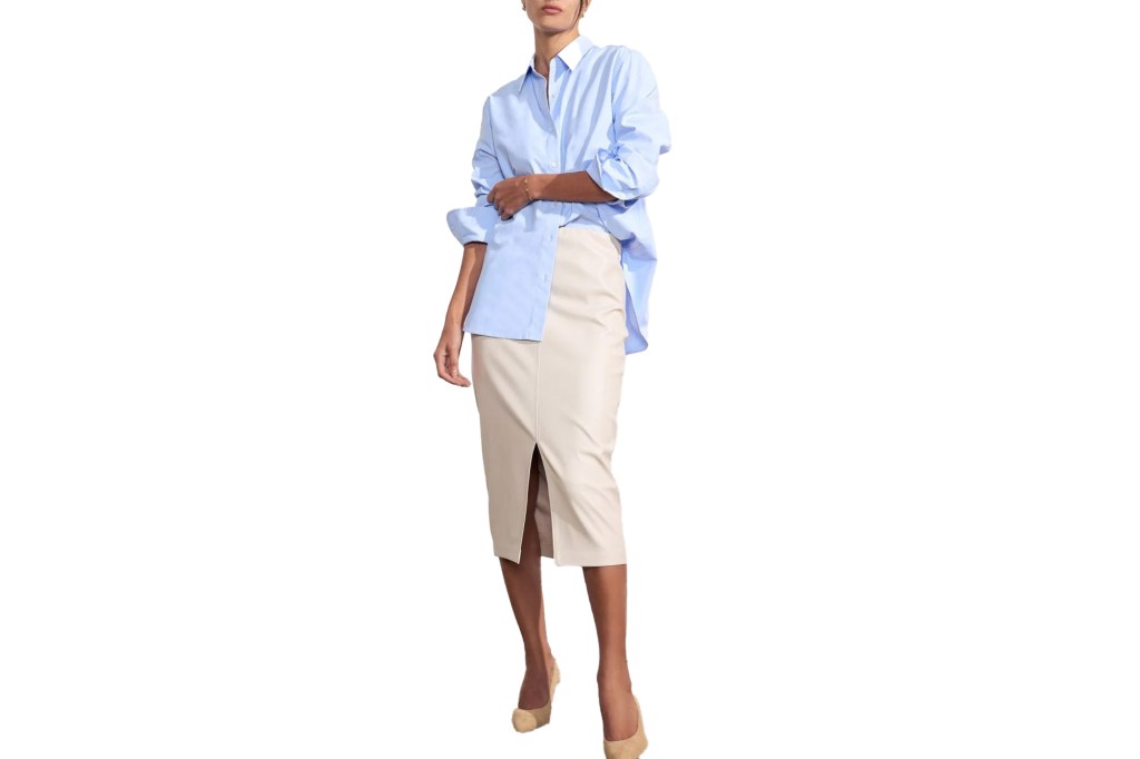 A person wearing a light blue button-up shirt and a cream-colored midi skirt with a front slit, paired with nude heels.