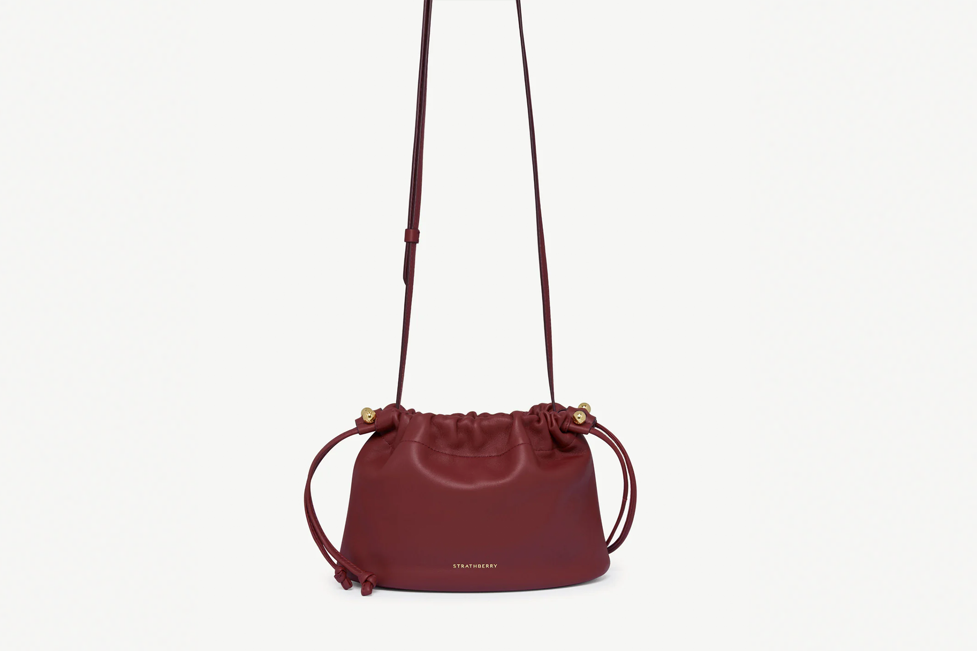 A burgundy Strathberry drawstring bag with a long strap.
