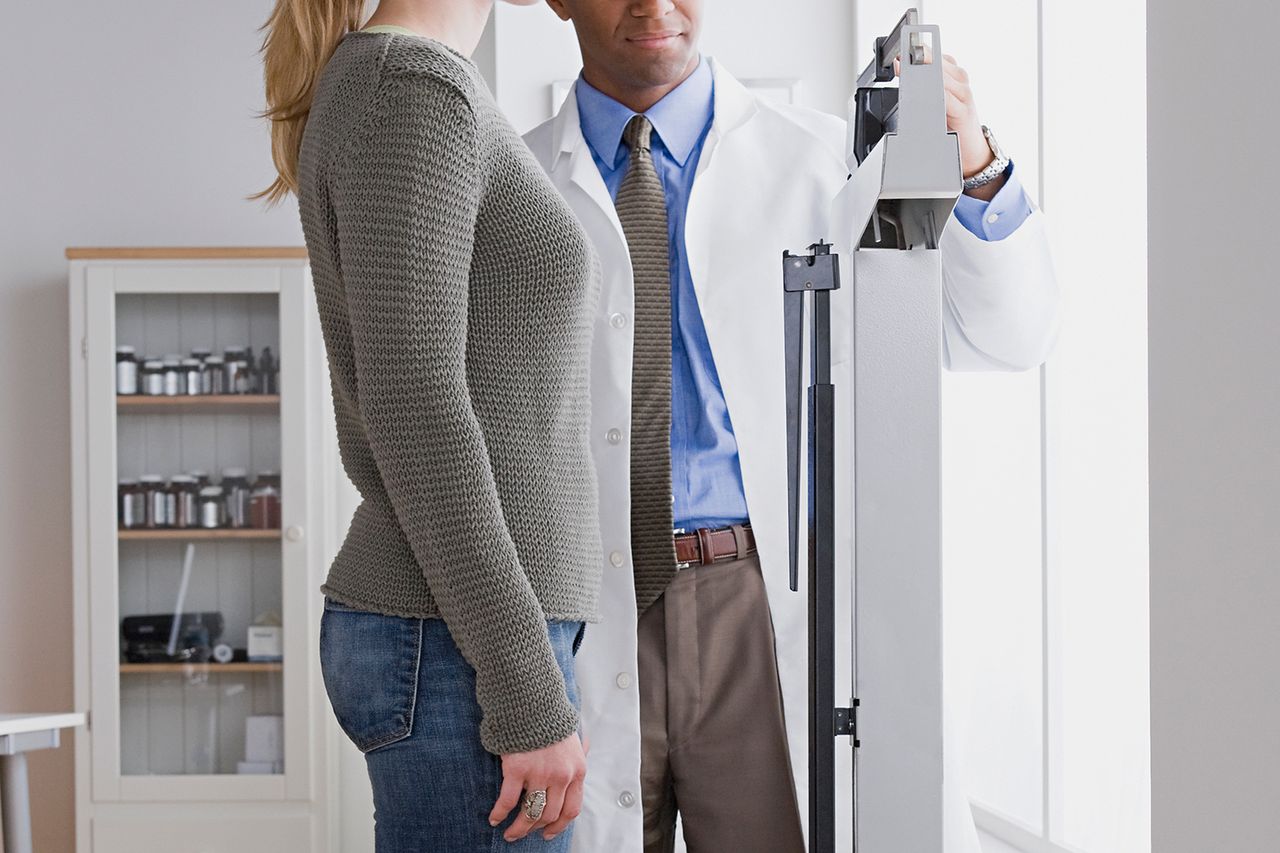 Stock image of a woman being weighed by her doctor.Credit: Getty