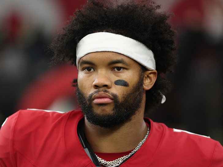 Kyler Murray is seen at a football game. He's wearing a red jersey and a white headband, and he has a patch of black face paint on his left cheek.