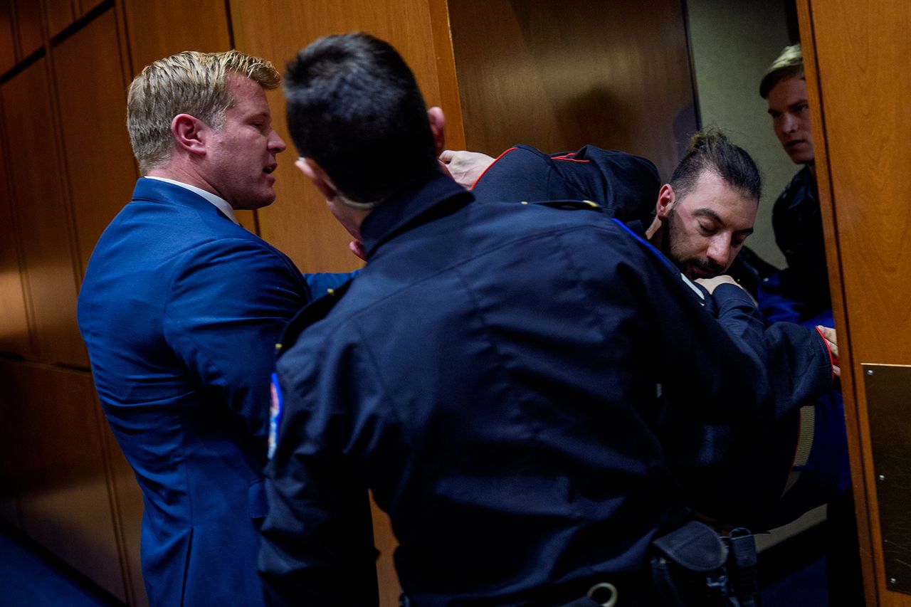 Brian McGinnis, a protester dressed in a military uniform, gets stuck in a door with Sen. Tim SheehyCredit: Andrew Harnik/Getty
