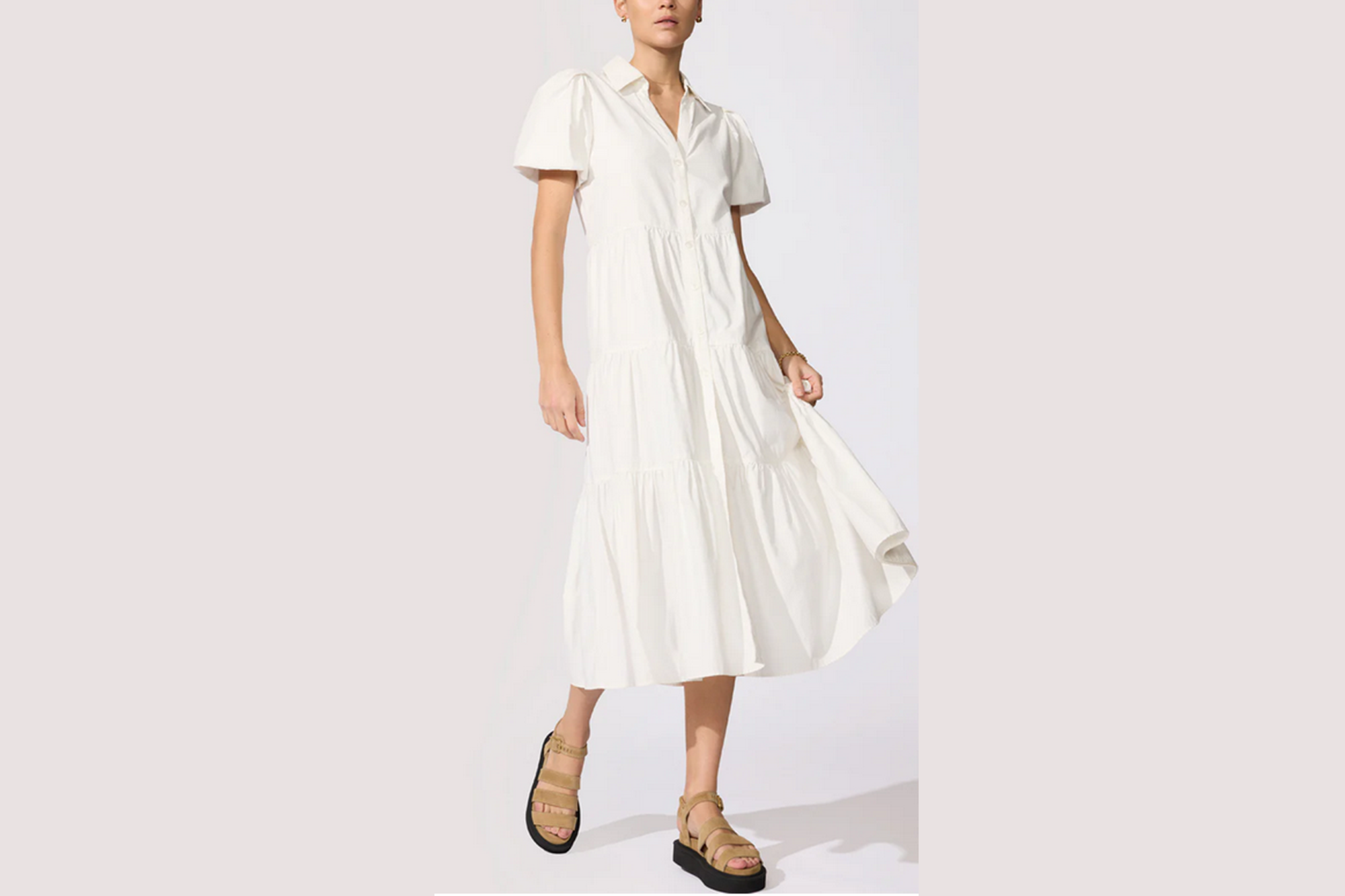A model wearing a white tiered midi dress with short puffy sleeves and tan platform sandals.