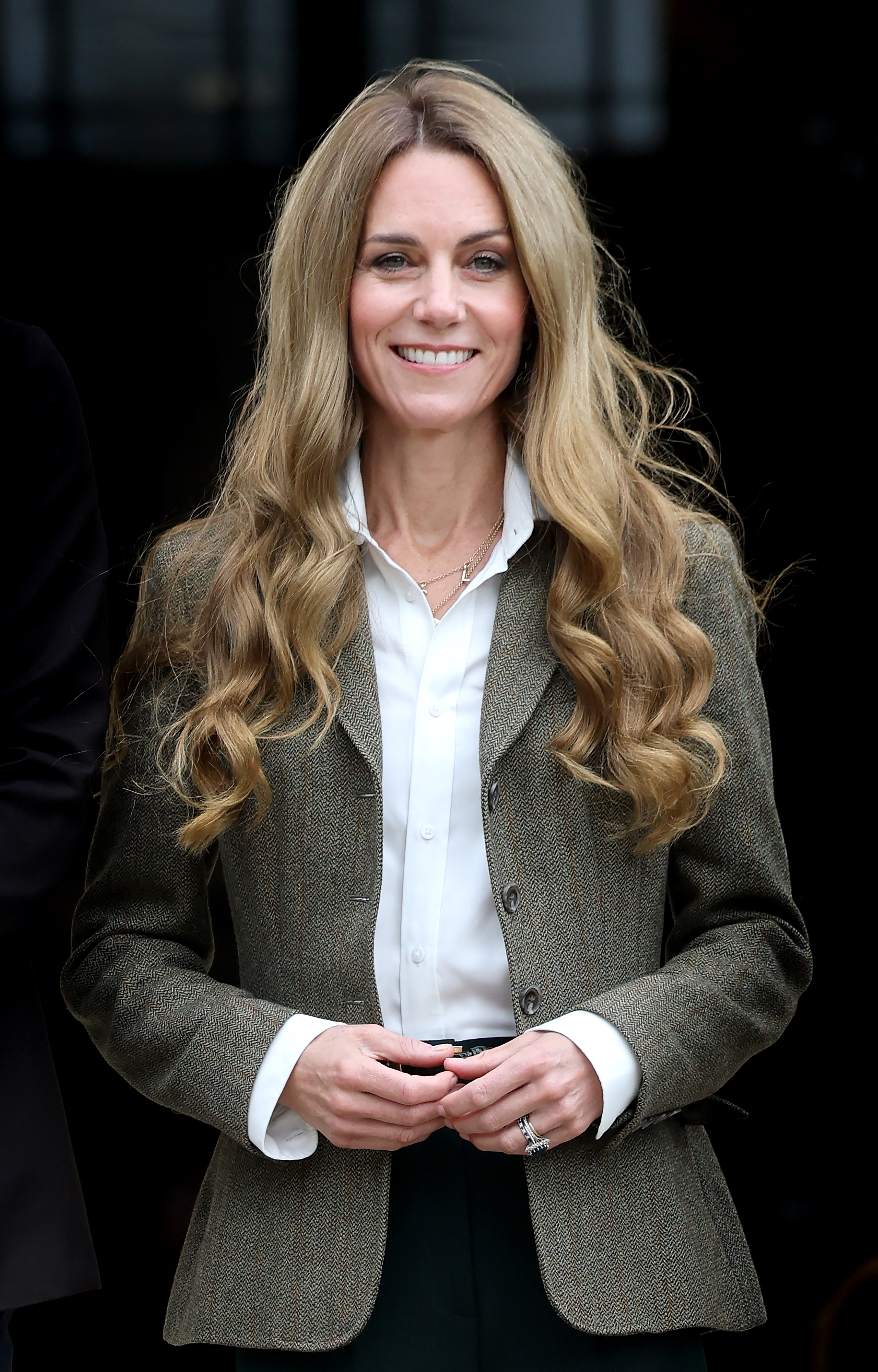 Catherine, Princess of Wales, smiles, wearing a white shirt and tweed blazer.