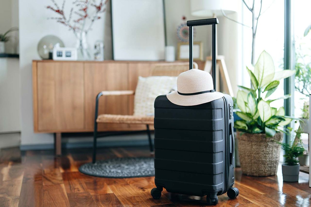 Still life of a black suitcase with a straw hat in the living room of an apartment. Airbnb (stock image)Credit: Getty