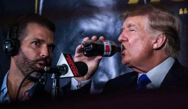 President Donald Trump drinks a soda as he hosts the Holyfield vs Belford boxing match live with commentary, next to his son Donald Trump jr. at the Hard Rock Live in Hollywood, Florida on September 11, 2021. Donald Trump sips a Diet Coke next to son Donald Trump Jr. at a 2021 boxing match in FloridaCredit: CHANDAN KHANNA/AFP via Getty