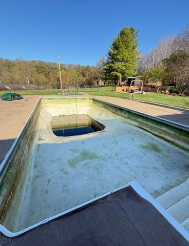 Empty swimming pool in an outdoor setting with buildings and trees in the background Alyssa Lynn Hartrick cleaning out the poolCredit: Alyssa Lynn Hartrick
