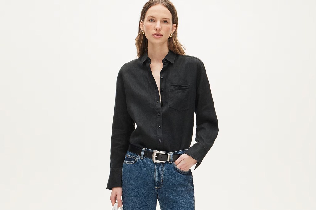 Woman wearing a black linen shirt, blue jeans, and a black belt.