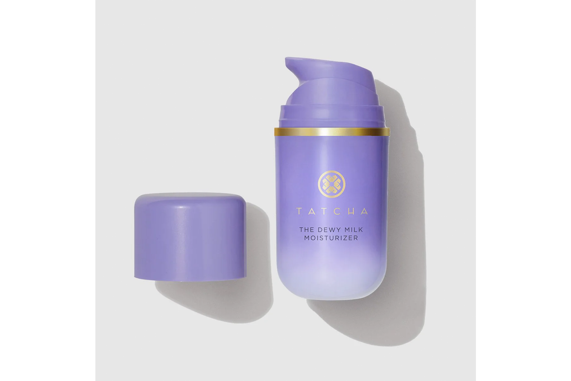Tatcha The Dewy Milk Moisturizer in a purple bottle with a gold band and a detached purple cap.