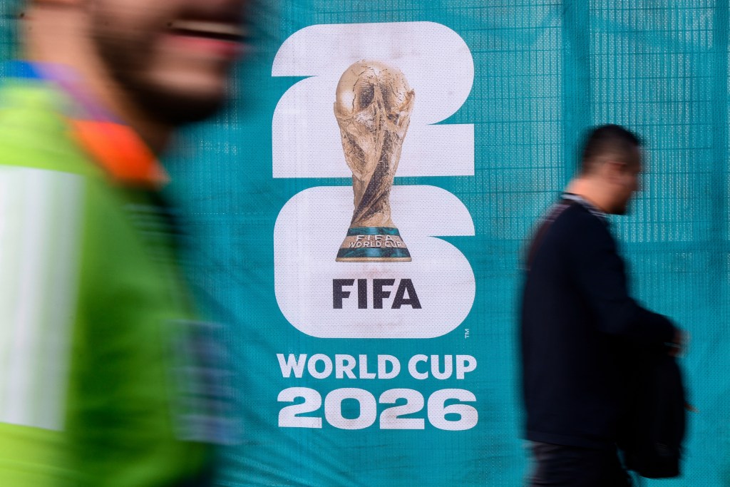 Pedestrians walk past an official competition logo on a fence ahead of the 2026 World Cup Group A football match between Mexico and South Africa at the Mexico City Stadium in Mexico City on June 11, 2026. (Photo by Rodrigo Oropeza / AFP)