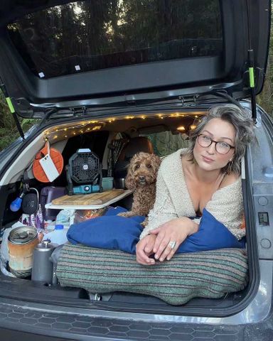 Woman Embraces Nomadic Life After Moving Into Her Car Due to High Cost of Living Bella Roams and her dog Lyla in her Subaru.Credit: Bella Roams