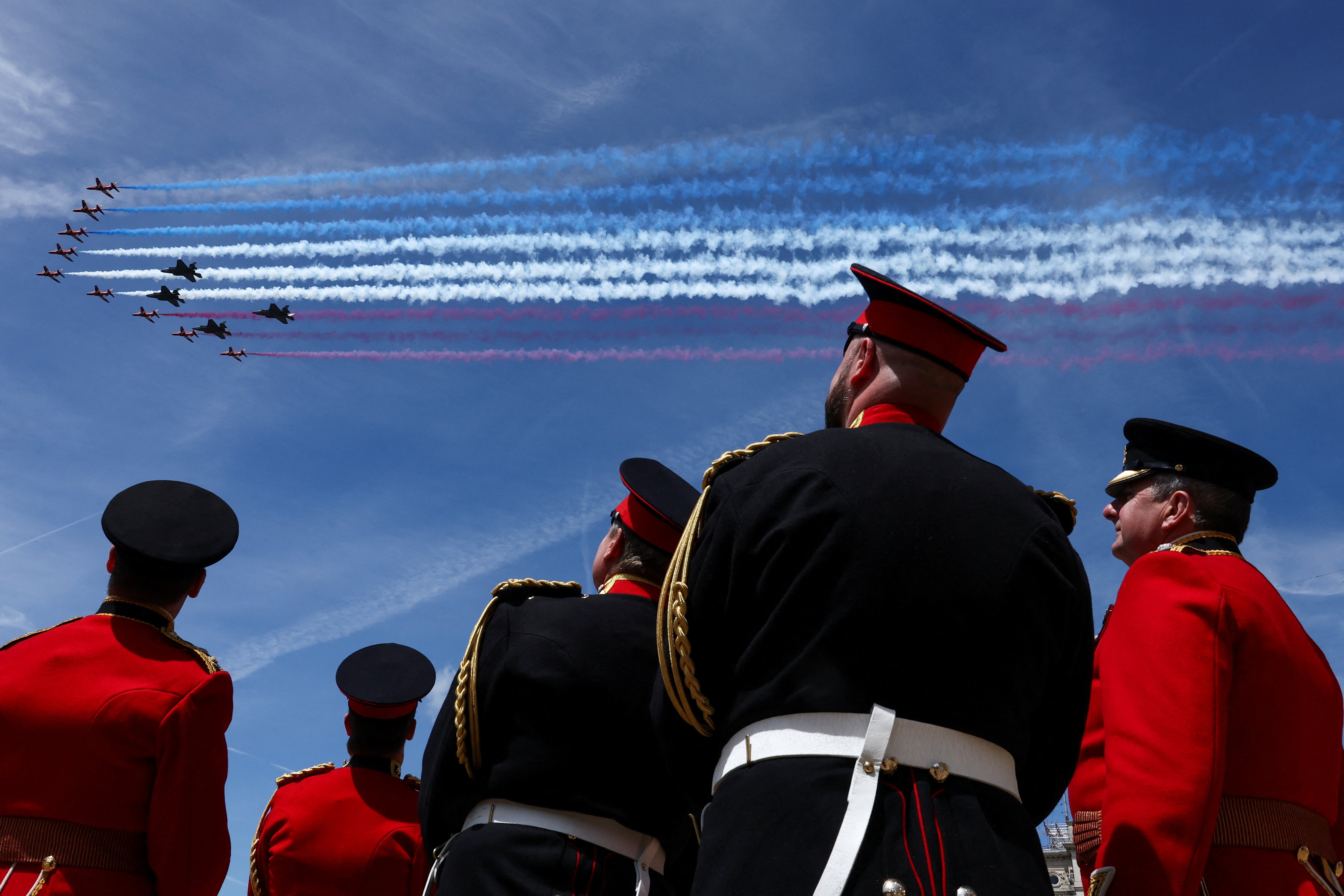 Members of the British military watch the Red Arrows perform a flypast during the Trooping the Colour parade.