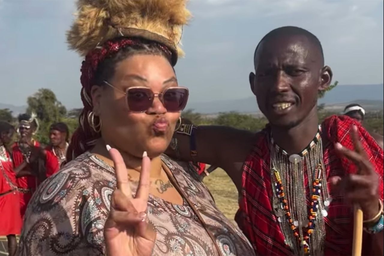 A woman making a peace sign poses with a man dressed in traditional attire outdoors with other people in the background Ayla GarciaCredit: Ayla Garcia/Instagram