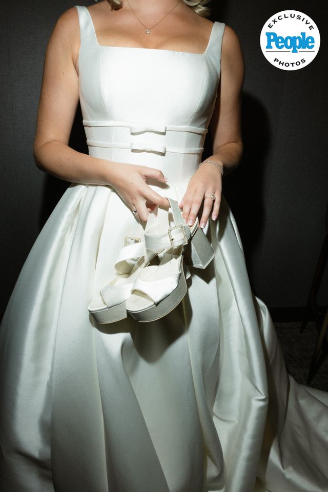 A bride in a wedding dress holding her shoes photo watermark from People Exclusive Mary Raclawski’s wedding gownCredit: Nikki Baker Photography