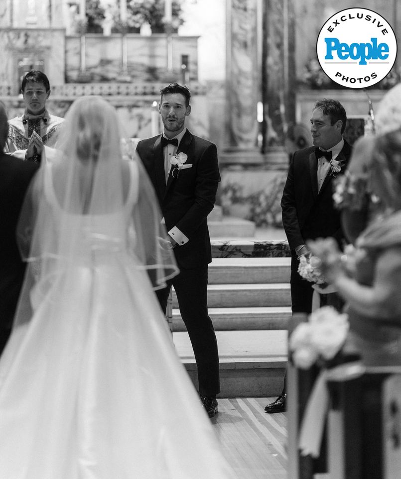 Wedding scene with bride walking down aisle towards groom and officiant in church setting Mary Raclawski walking down the aisleCredit: Nikki Baker Photography