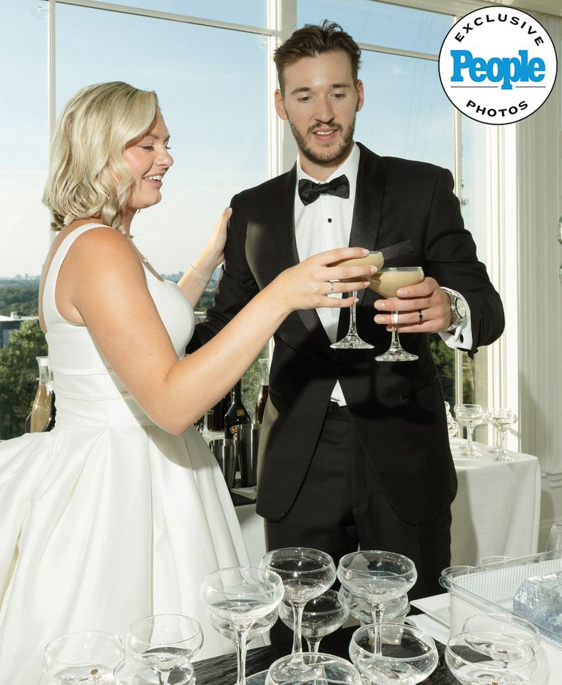 A bride and groom toast each other at their wedding reception with champagne glasses on the table in front of them Mary Raclawski and Brandon Bussi toasting with espresso martinisCredit: Nikki Baker Photography