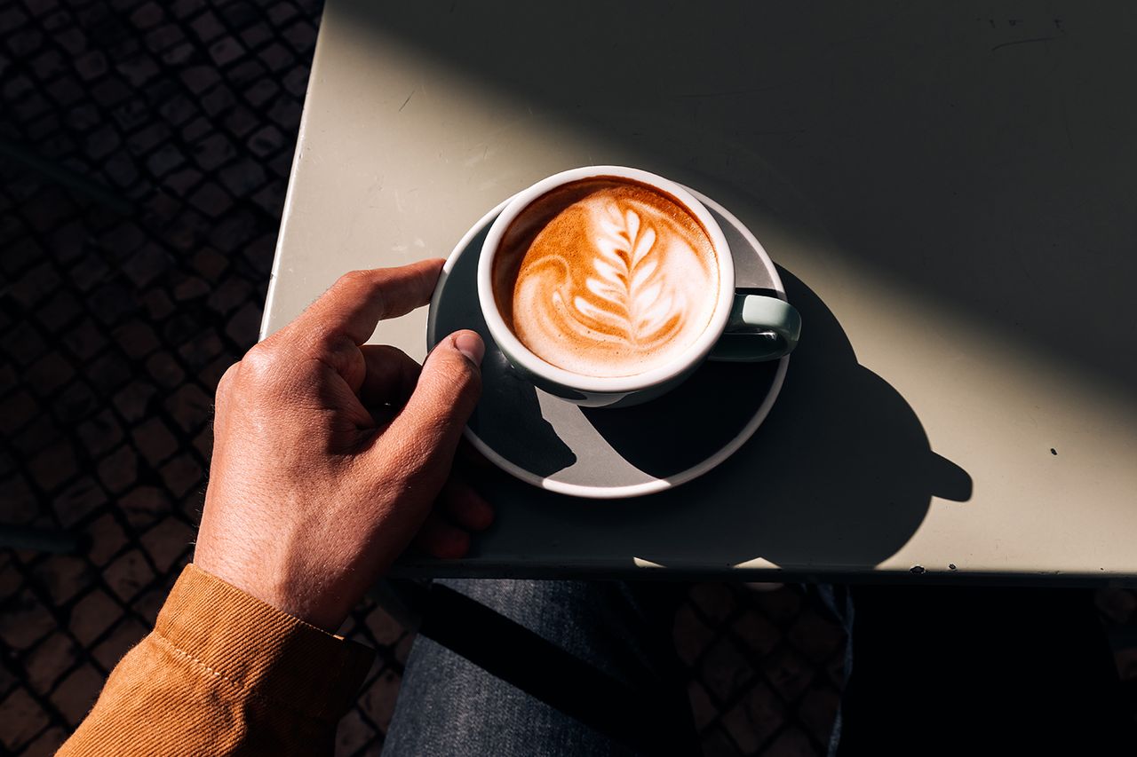 Man drinking latte at a sidewalk cafe on a sunny day, personal perspective view Cup of coffee (stock)Credit: Getty