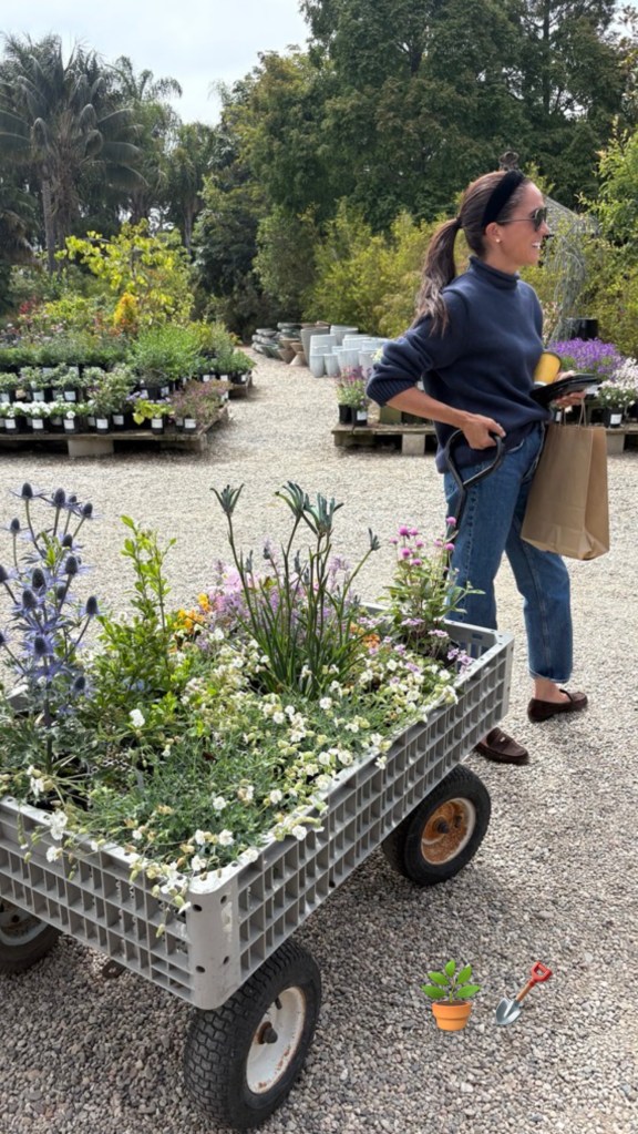 Meghan Markle pushing a wagon full of plants at a nursery.