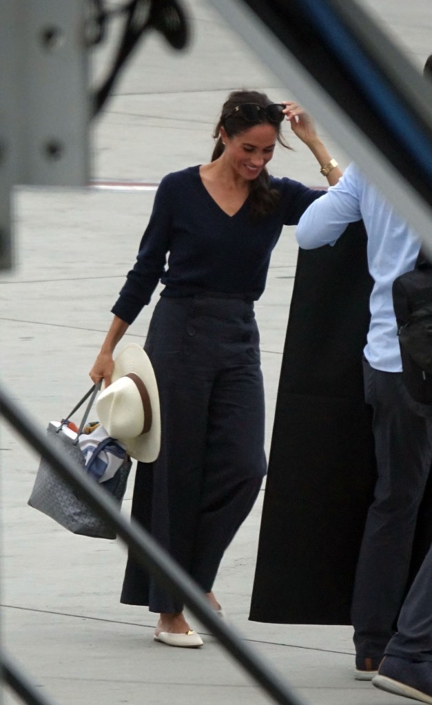 Meghan Markle at LAX, holding a bag and hat, en route to the Invictus Games.