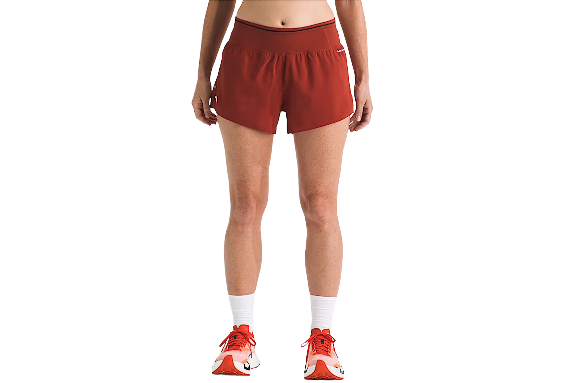 A person wearing rust-colored athletic shorts, white socks, and orange running shoes.