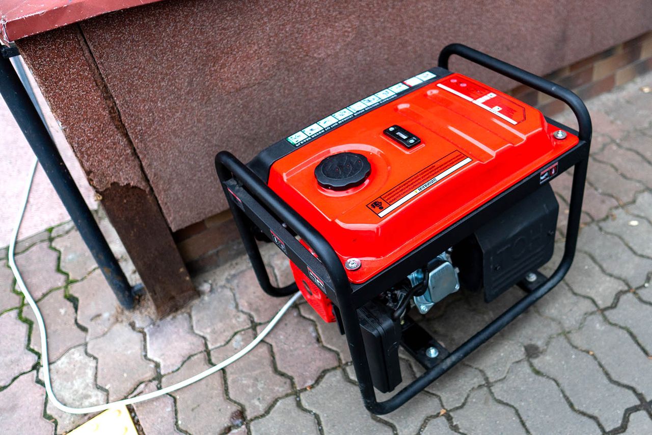 A red generator stands on the pavement beside a building. The generator is set up to provide electricity for work or events happening nearby. Portable generator (stock image)Credit: Getty
