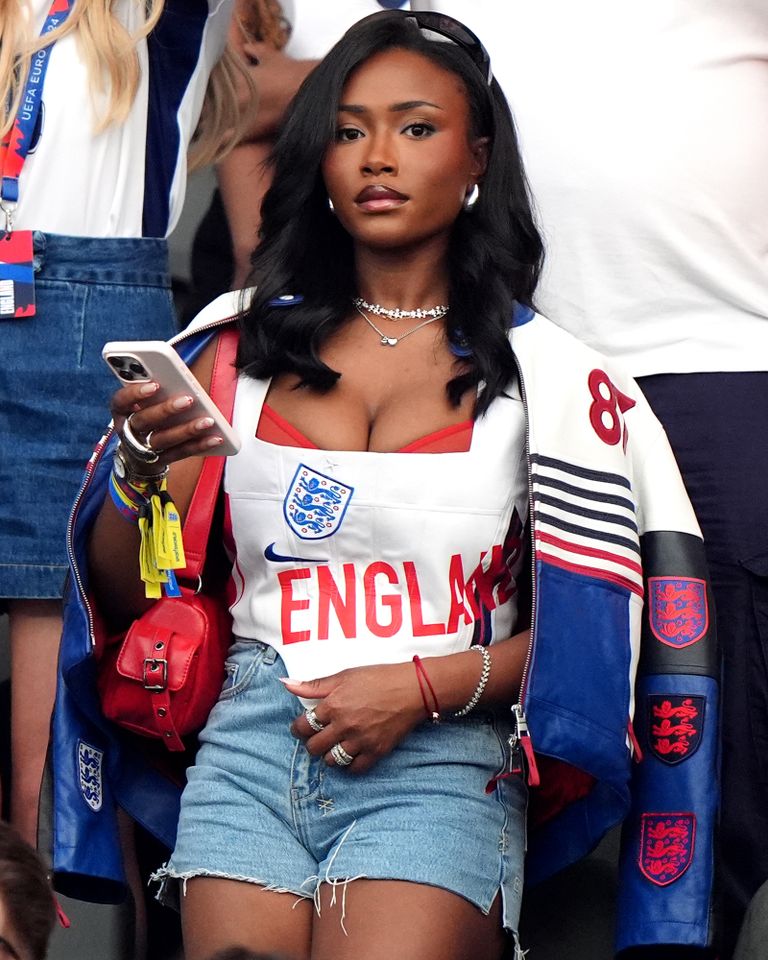 A person in a sports jersey and shorts holding a smartphone in a stadium setting Tolami Benson at the 2024 Euros.Credit: Bradley Collyer/PA Images via Getty
