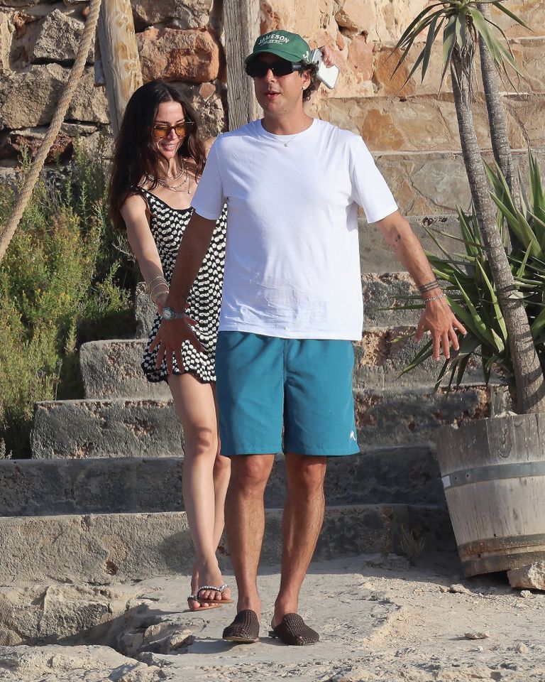 Two people walking outdoors down stone steps one wearing a summer outfit with shorts and the other in a dress Ana de Armas and Beto Montenegro in Formentera on Aug. 2Credit: COBRA TEAM / BACKGRID