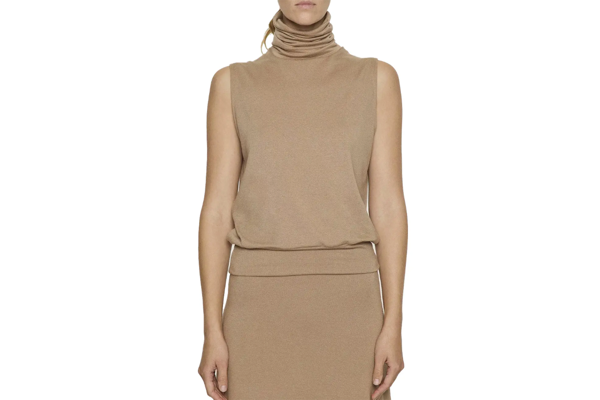 A woman modeling a sleeveless beige turtleneck shirt and matching skirt.