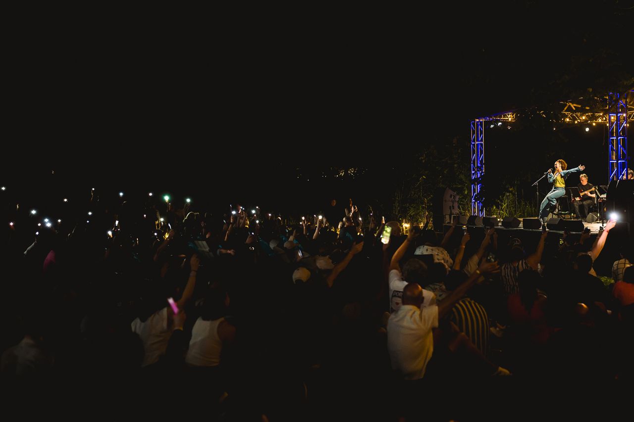 A nighttime outdoor concert with a performer on stage and an audience holding lights Solea Pfeiffer sings at the Campfire Stage at The Festival on Friday, Aug. 14 at Hutton Brickyards Riverfront Hotel + Venue in Kingston, N.Y.