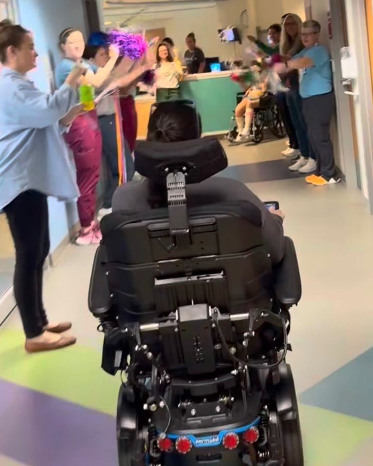 A person in a motorized wheelchair is greeted by a group of people lined up in a hallway Abby BuellCredit: gofundme