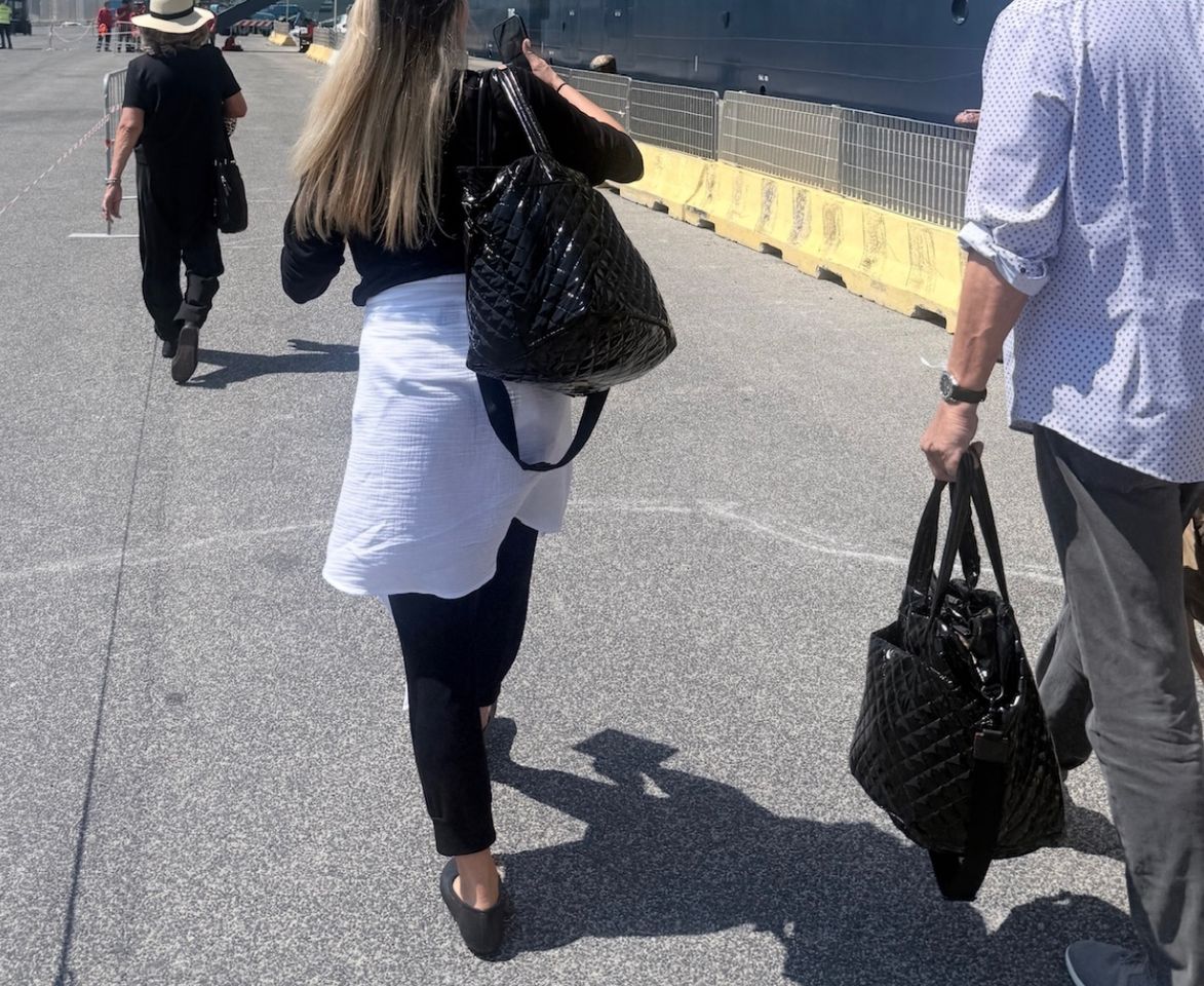 People walking outdoors carrying tote bags rear view Credit: People