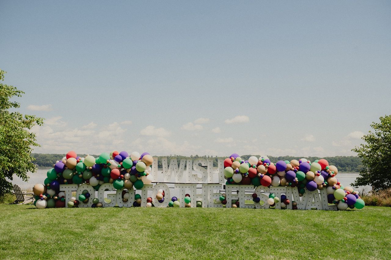 A decorative sign with balloons on a grassy field near a body of water under an open sky A view from The Festival at Hutton Brickyards Riverfront Hotel + VenueCredit: Michaelah Reynolds