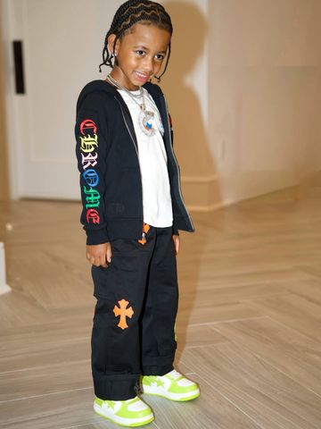 Cardi B's son Wave standing indoors wearing a hoodie and pants with cross patterns with braided hair and smiling Cardi B’s son WaveCredit: cardi b/instagram