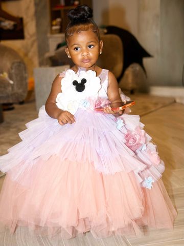 Cardi B's daughter Blossom in a formal dress holding an item inside a room with furniture visible in the background Cardi B’s daughter Blossom, 2Credit: cardi b/instagram