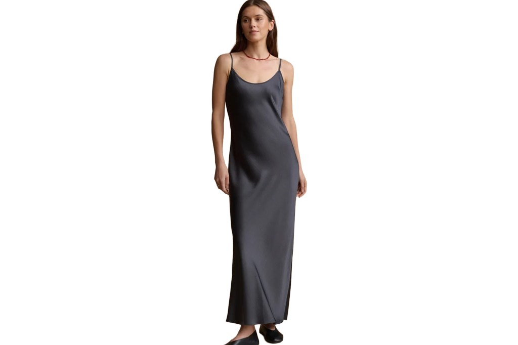 Woman in a dark gray slip dress and black flats.