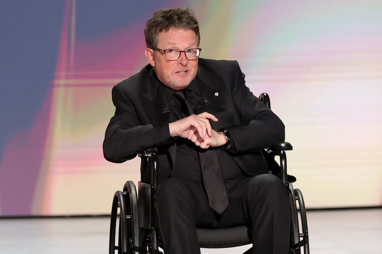 A person in a wheelchair speaking at an event on a stage with a colorful background Credit: Kevin Winter/Getty