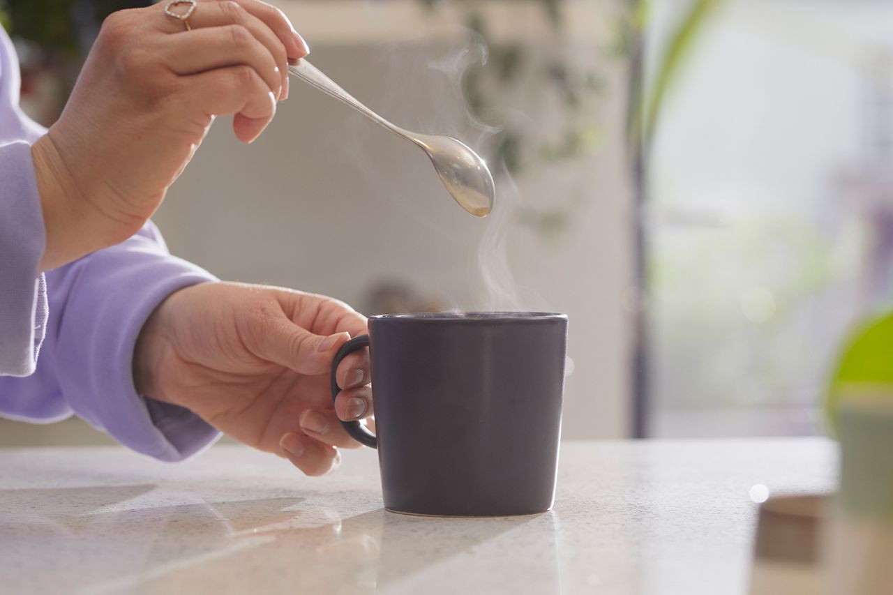 Stock image of a woman stirring a hot drinkCredit: Getty