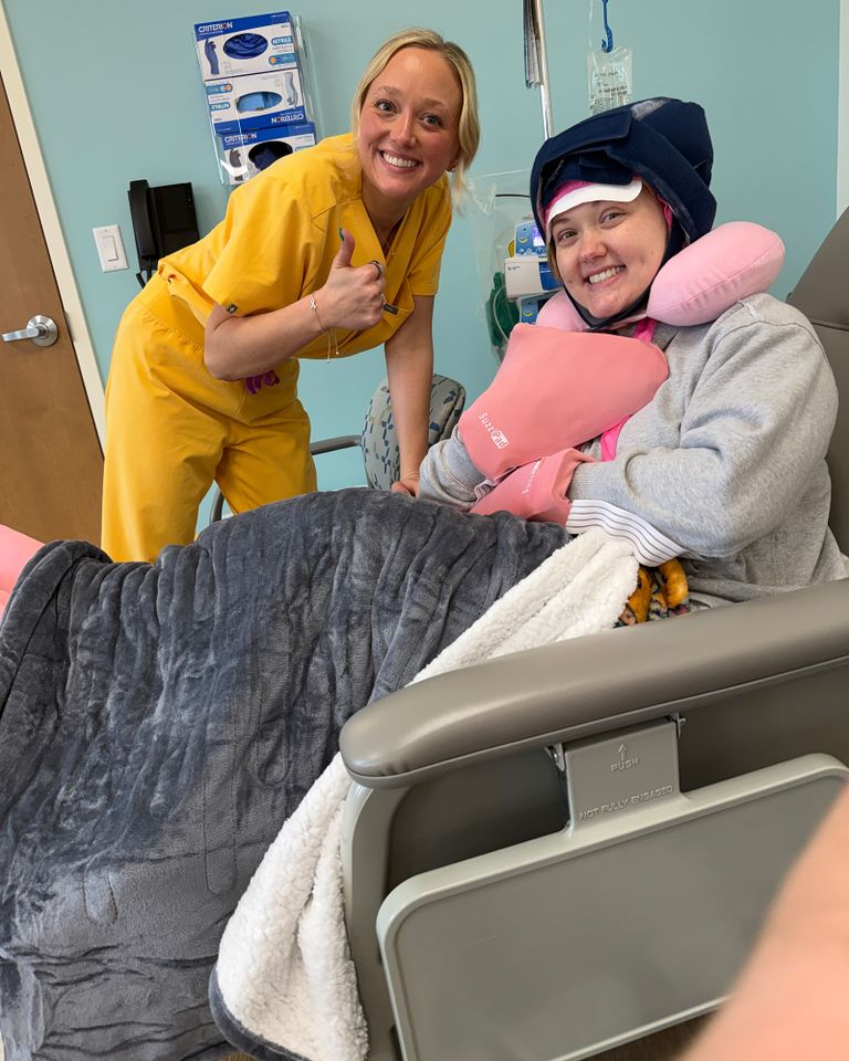 A smiling caregiver posing with a patient seated and covered with a blanket in a medical setting Abby WilsonCredit: Courtesy of Abby Wilson