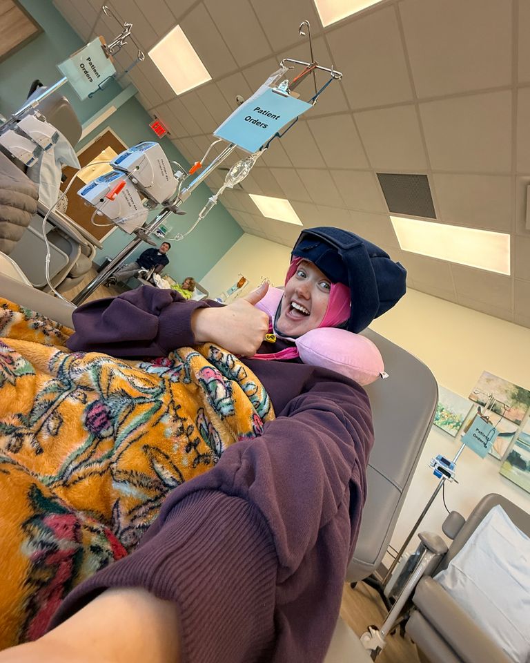 Person sits in a medical setting receiving treatment wearing a head covering and smiling with a thumbsup gesture Abby WilsonCredit: Courtesy of Abby Wilson