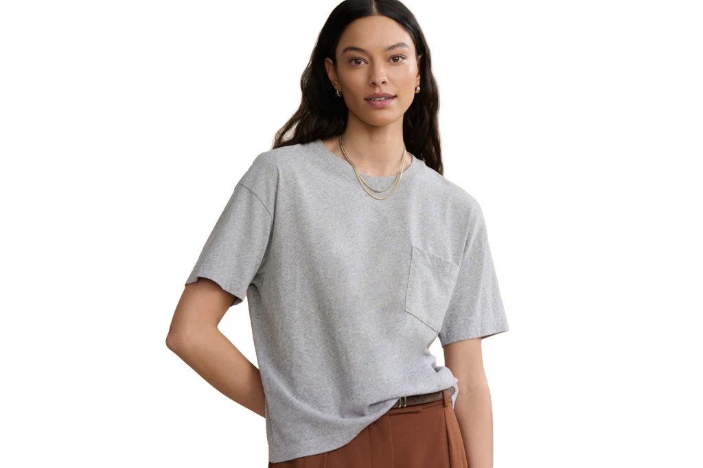 A woman wearing a gray short-sleeve shirt with a pocket and brown pants.