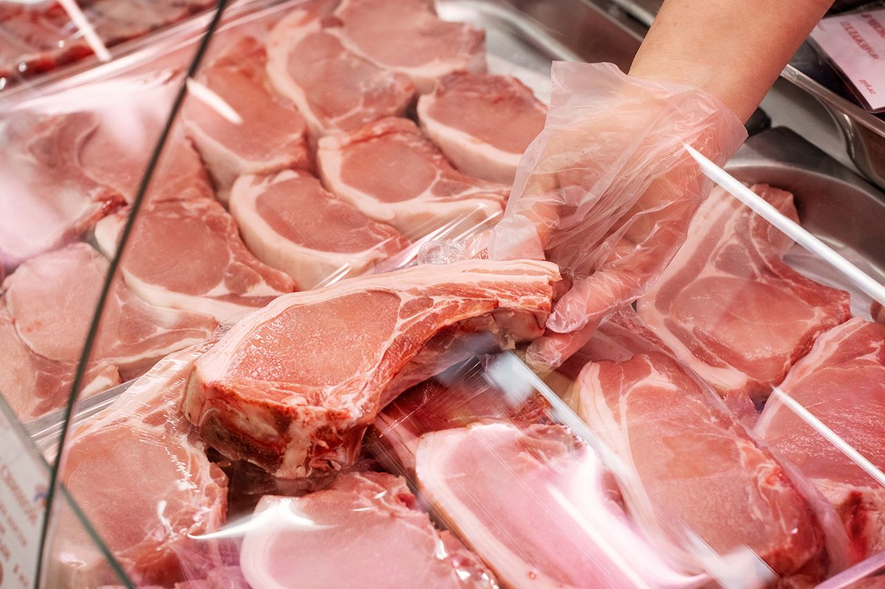 A close-up of a gloved hand selecting fresh pork chops The recall has been classified at the USDA’s highest warning levelCredit: Getty