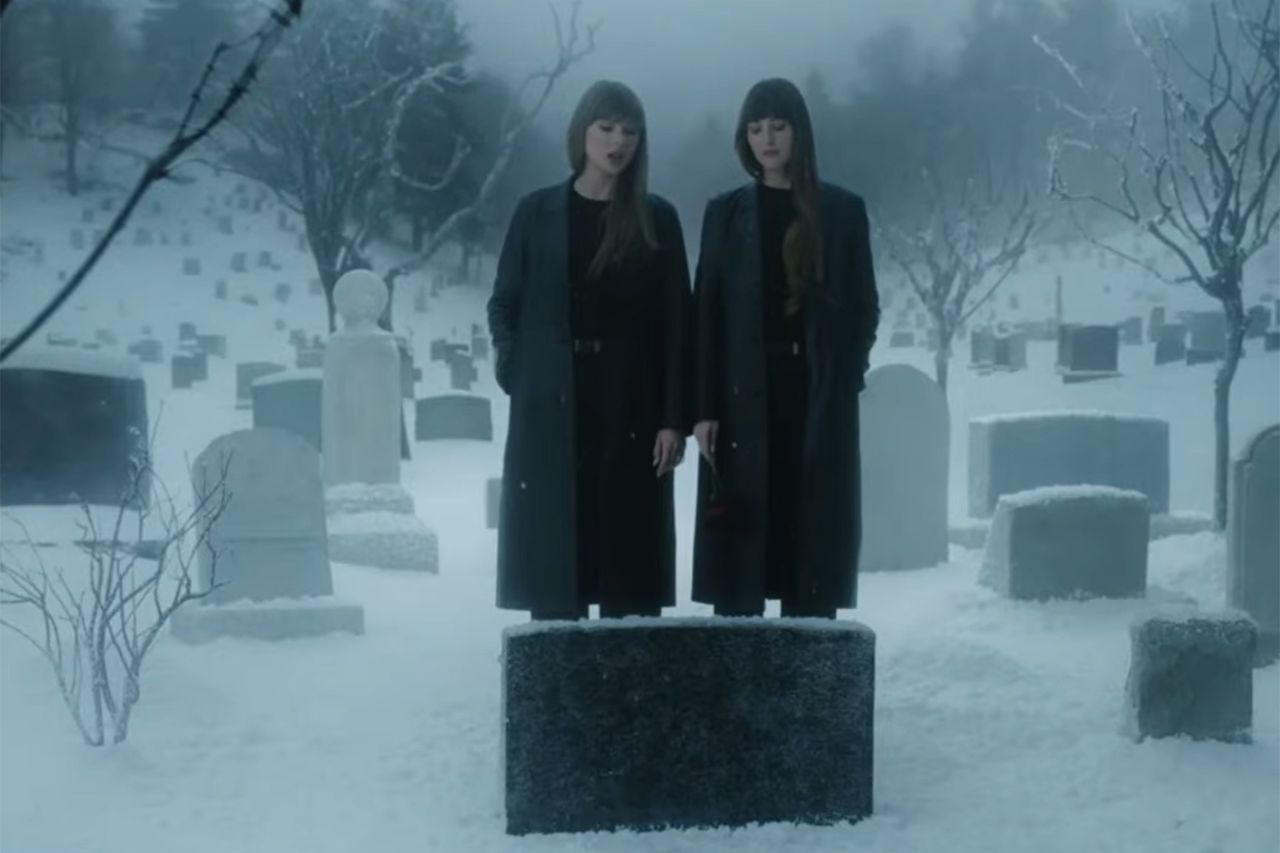 Two individuals in dark coats standing in a snowy cemetery near a gravestone Taylor Swift and Dakota JohnsonCredit: mtv